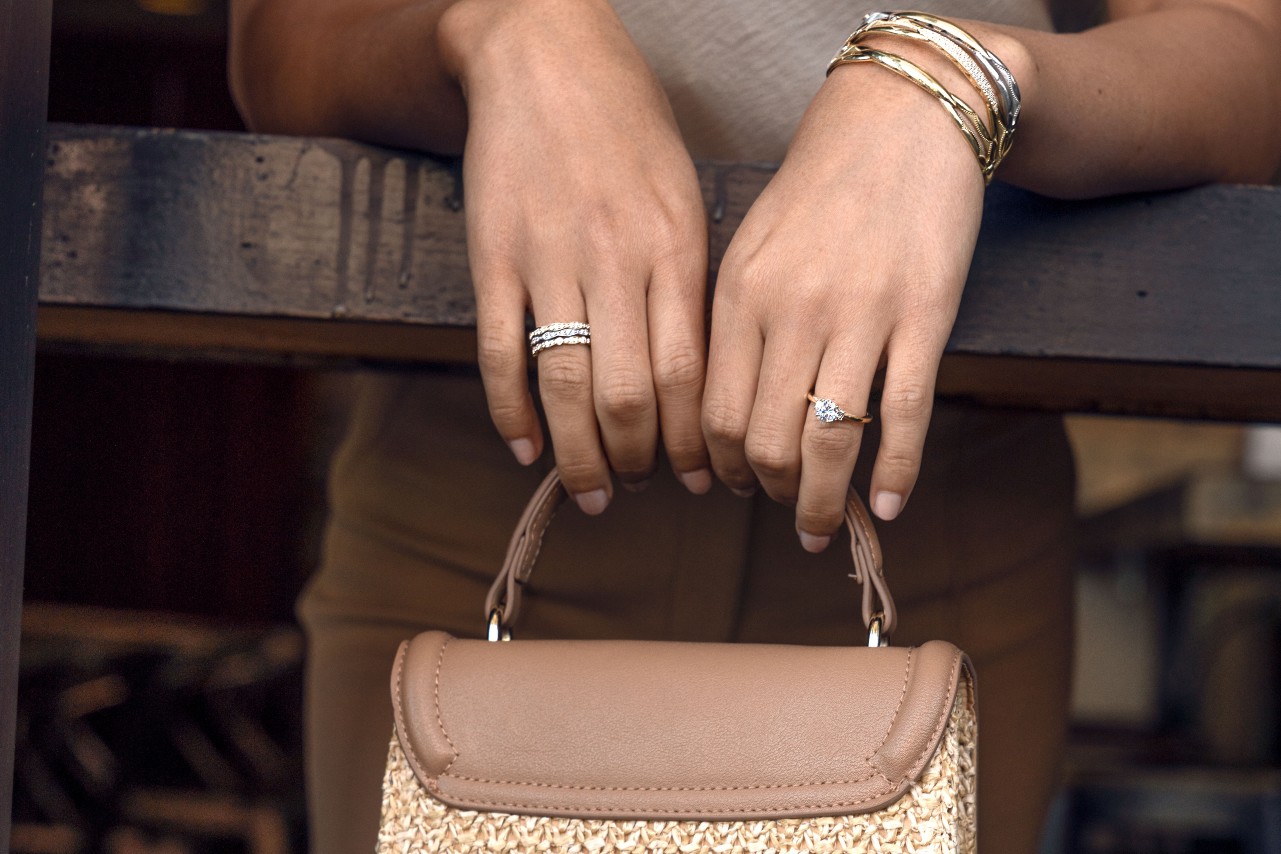 a woman’s hands holding a purse over a rail and wearing TACORI fashion jewelry