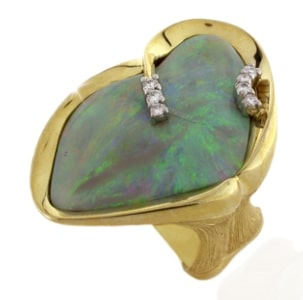 A brushed gold fashion ring features a large opal stone and diamond.