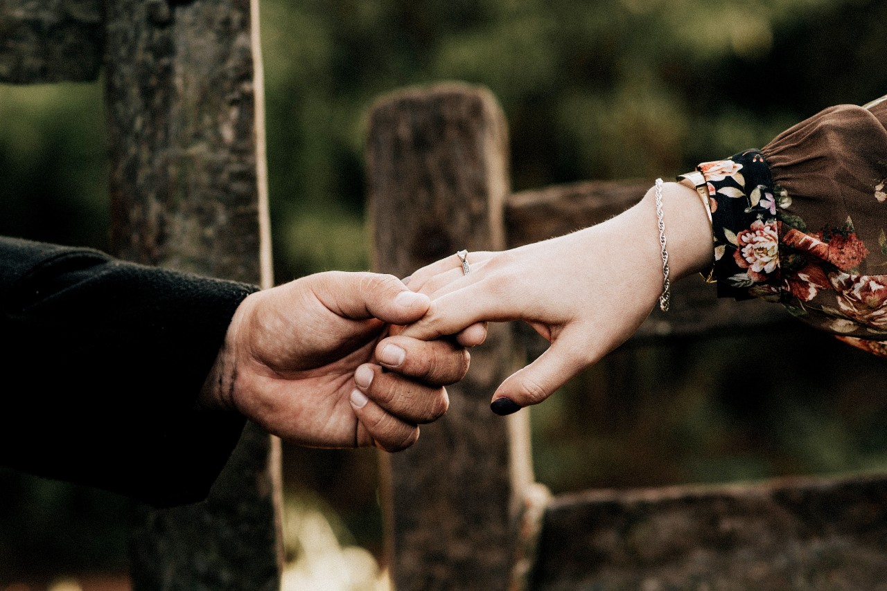 A woman holds hands with her fiance outside while wearing a silver rope chain bracelet.