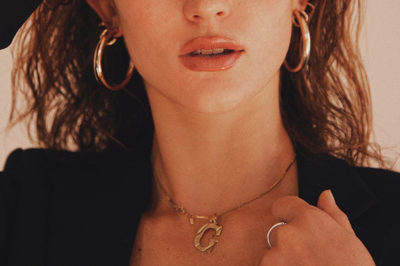 close up image of a woman wearing a black blazer and gold jewelry
