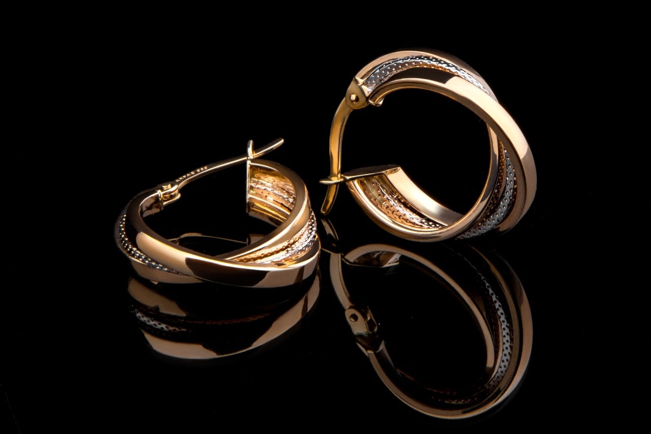 pair of yellow and white gold hoop earrings against a black background