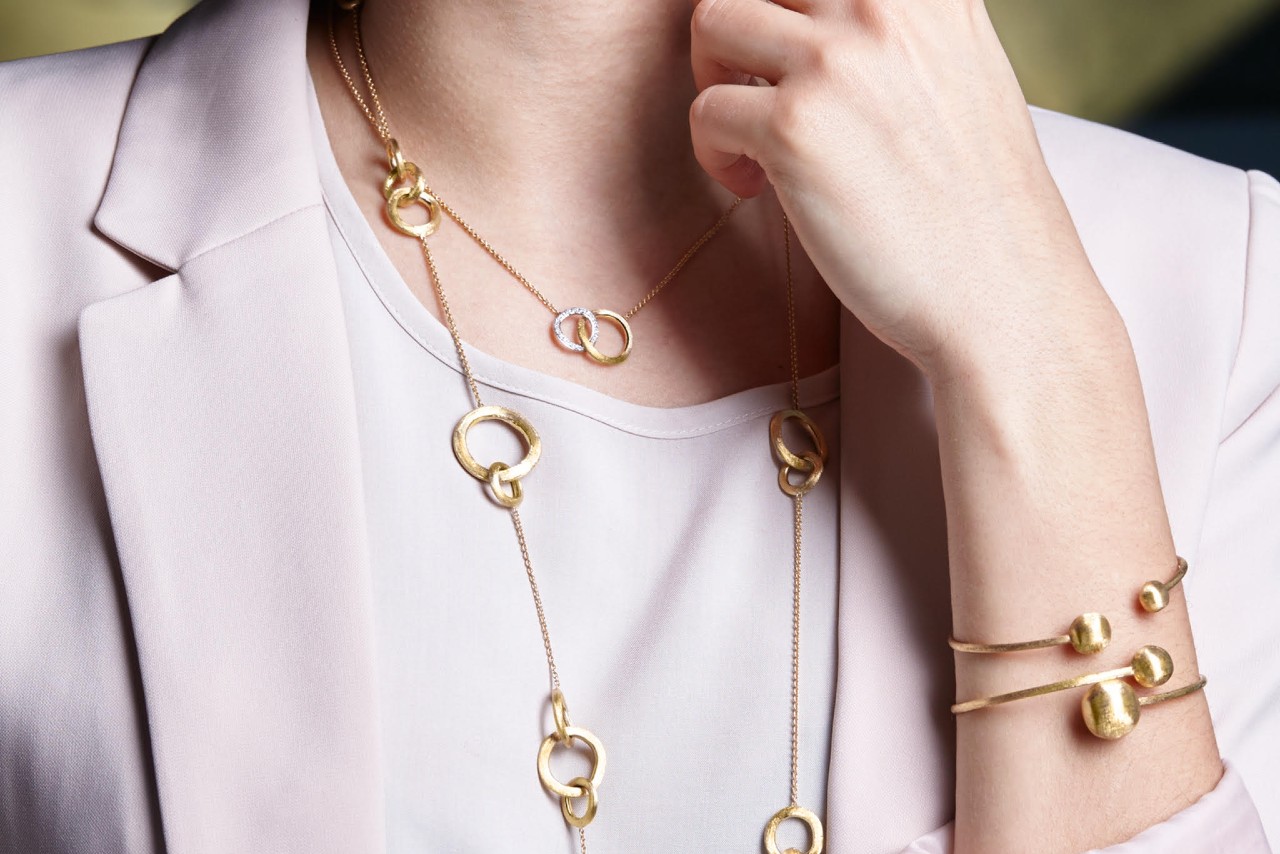 a woman wearing multiple gold bangles along with a couple gold necklaces