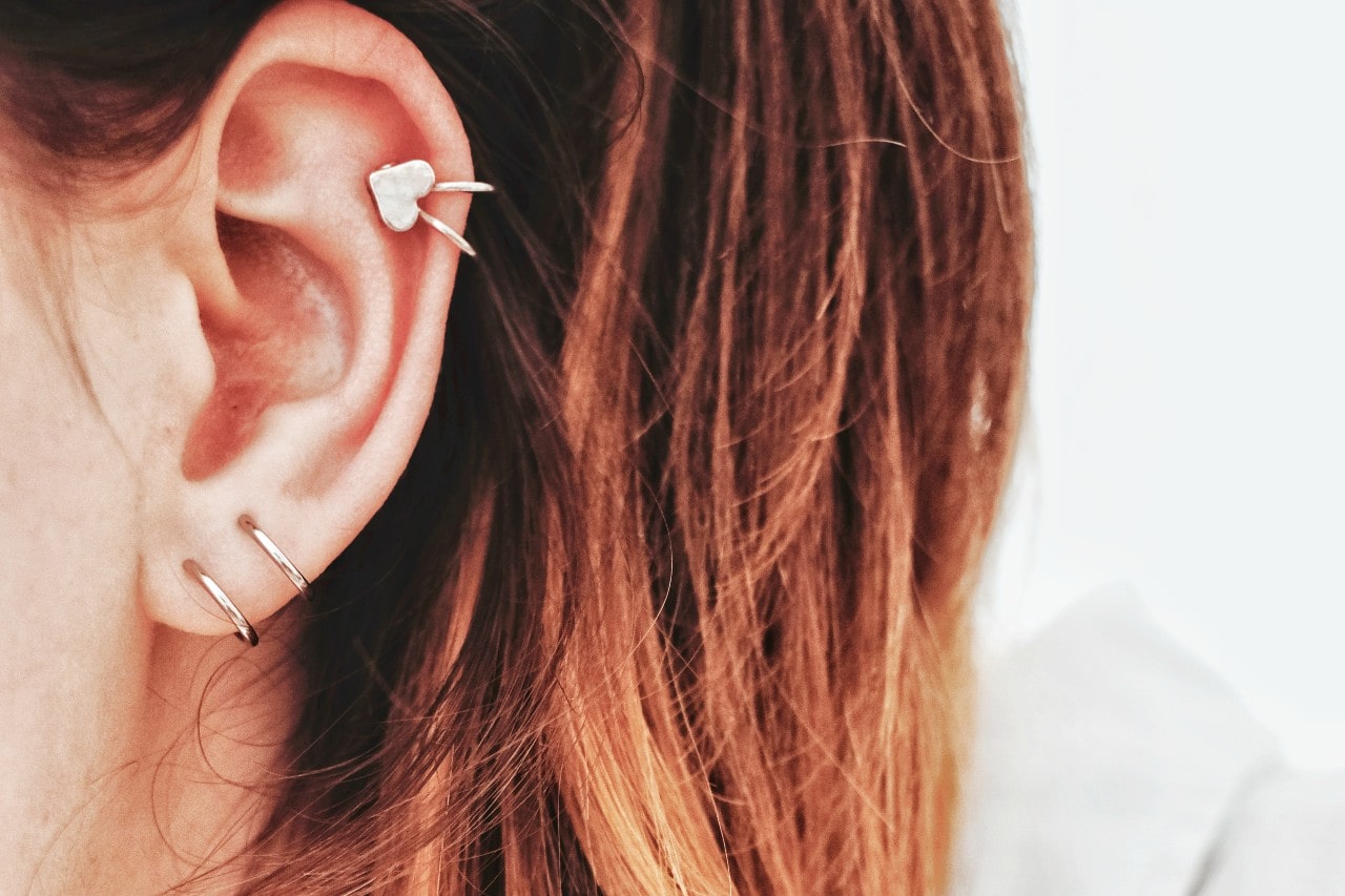 close up image of a woman’s earring donning three rose gold earrings