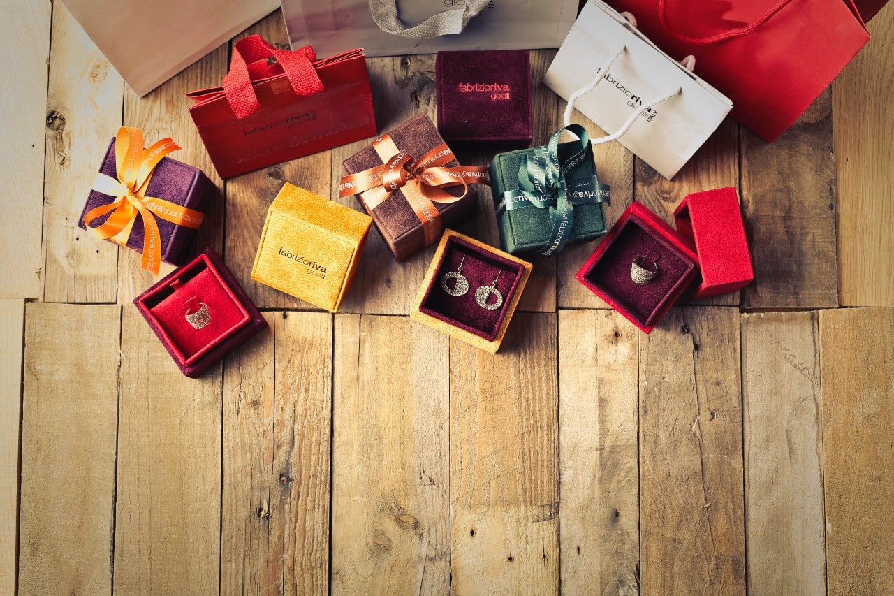 Elegant wooden floor with colorful gift boxes and shopping bags showcasing jewelry, such as earrings and rings.