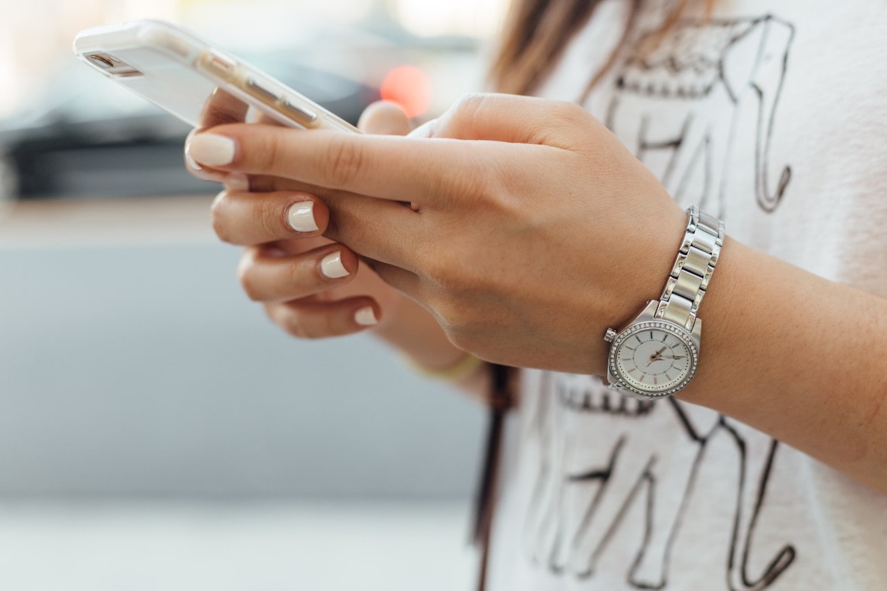 lady holding a cell phone and wearing a luxury watch