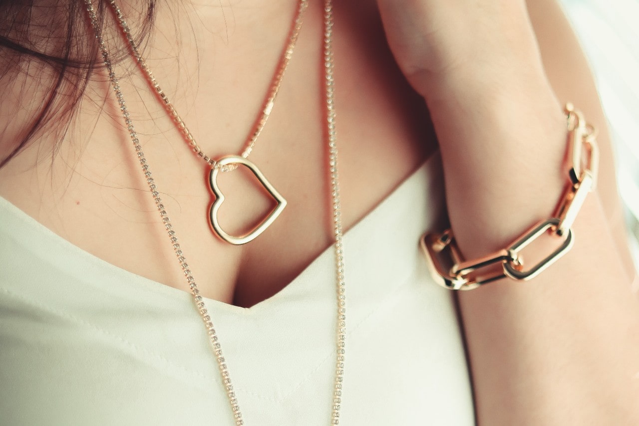 a woman wearing a gold heart necklace and chunky chain bracelet a woman wearing a gold heart necklace and chunky chain bracelet