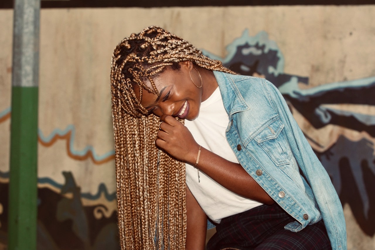 a woman leaning over and laughing, wearing minimal gold jewelry