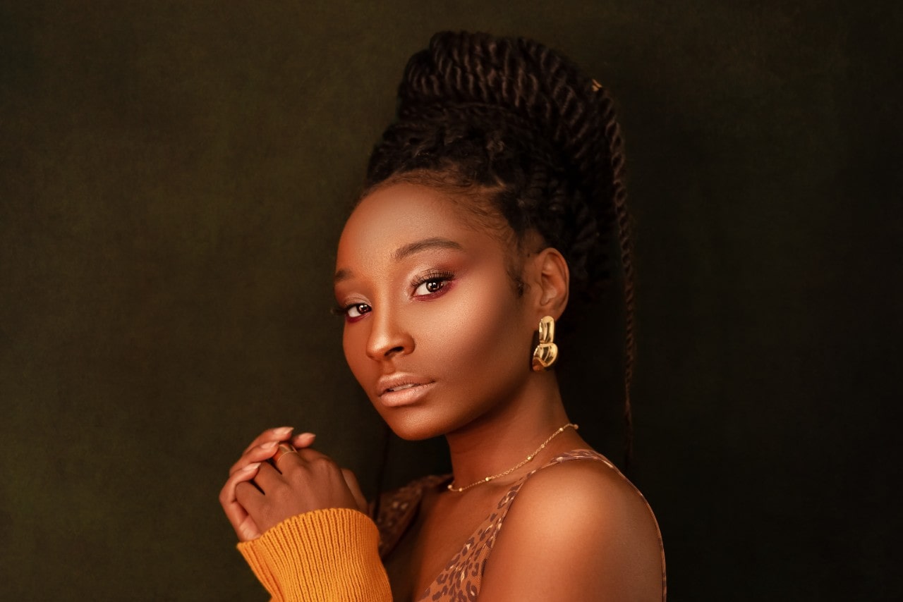 a woman looking into the camera wearing bold gold earrings and a fine gold necklace