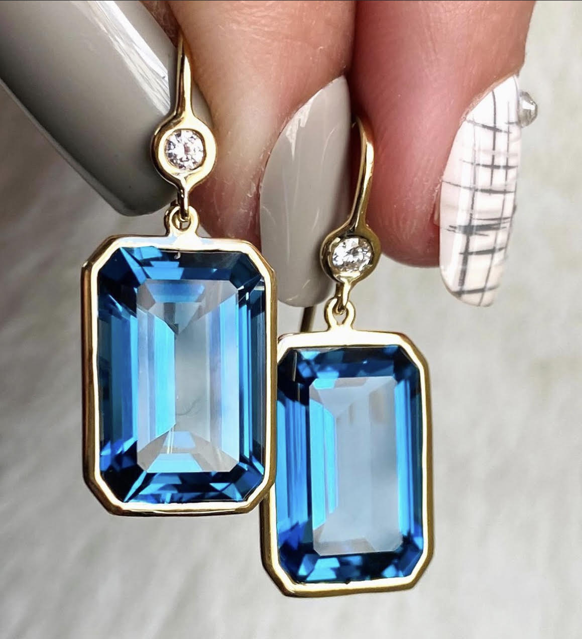 A pair of blue gemstone drop earrings with diamond details. A pair of blue gemstone drop earrings with diamond details.