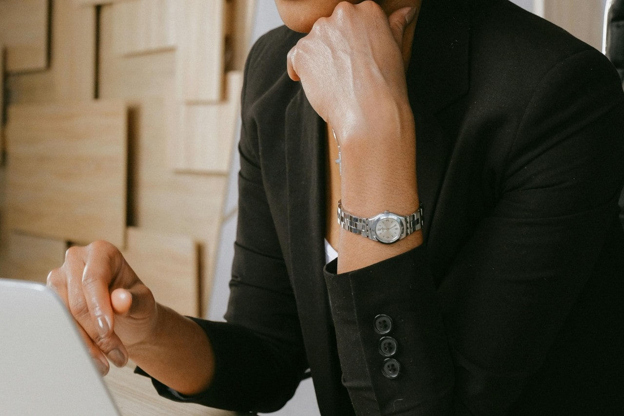 a woman in a black suit looking at a computer and wearing slim silver watch a woman in a black suit looking at a computer and wearing slim silver watch