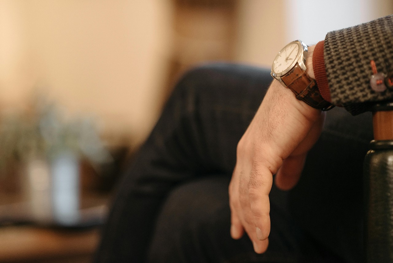 a man’s wrist resting on a chair arm and wearing a silver vintage watch a man’s wrist resting on a chair arm and wearing a silver vintage watch