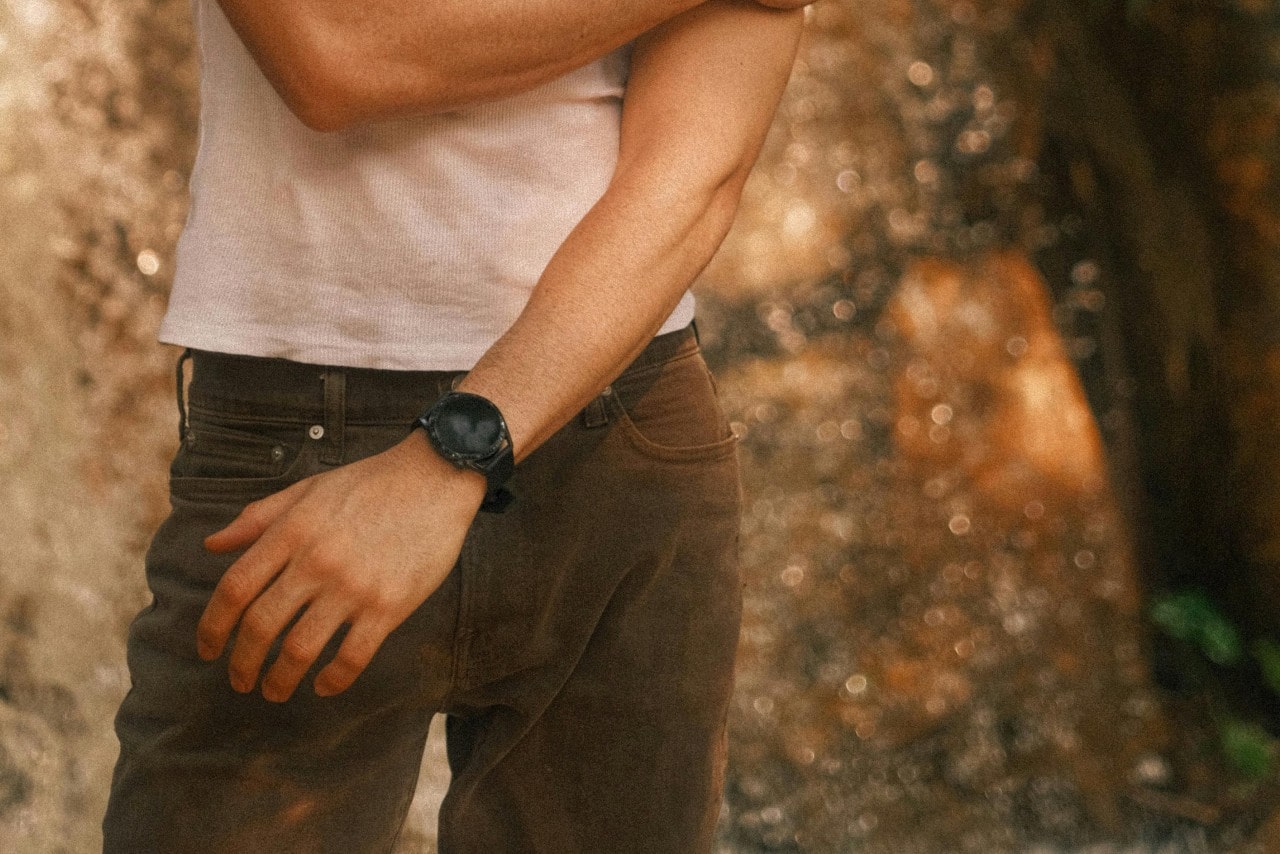 a man in a white shirt and brown pants standing outside with a black watch on a man in a white shirt and brown pants standing outside with a black watch on