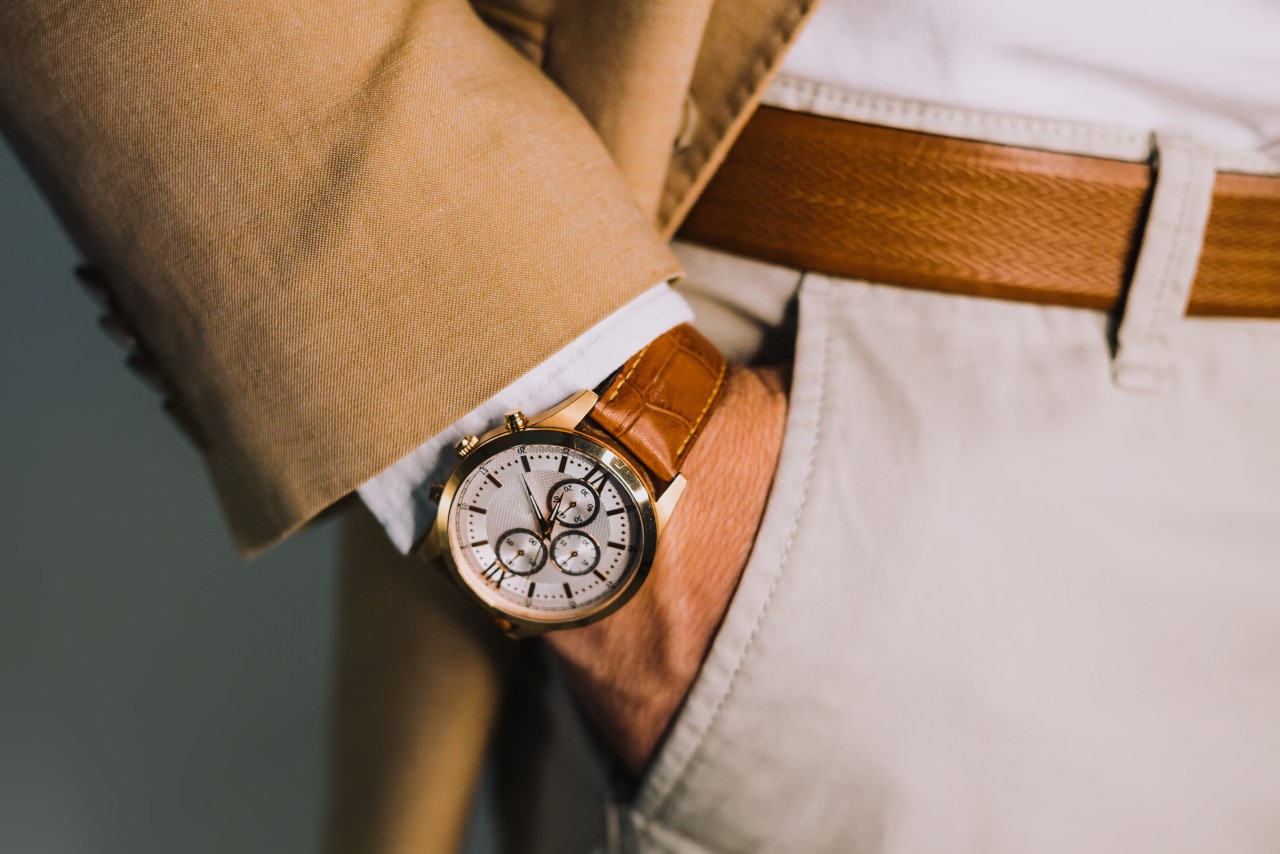 A close up of a man’s hand in the pocket, showcasing leather wristwatch with several complications and white dial. A close up of a man’s hand in the pocket, showcasing leather wristwatch with several complications and white dial.